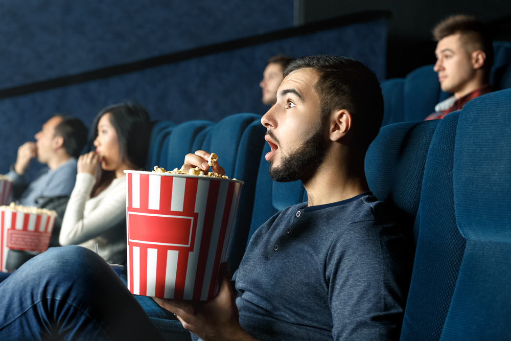 Young-man-surprised-at-movie-theater-while-eating-popcorn